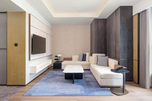 a living room with a couch and a tv at Luoyang Marriott Hotel in Luoyang