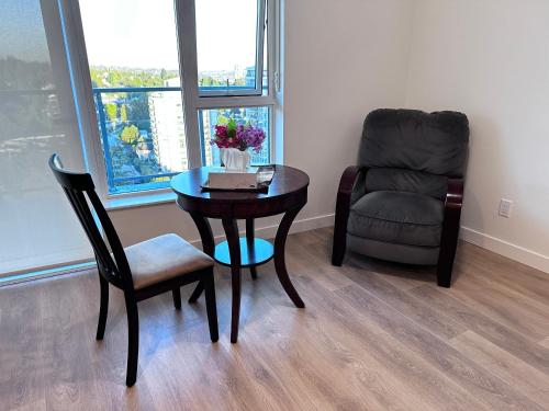 a table and a chair in a living room with a chair and a table at New condo near Lougheed Mall & SFU in Coquitlam