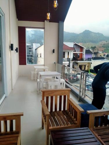 a balcony with benches and tables and a view of the water at Maorin Guest House in Dieng