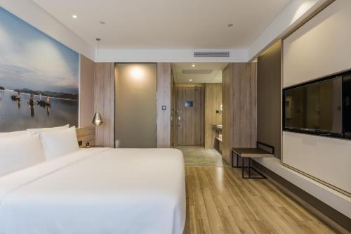 a bedroom with a large bed and a flat screen tv at Atour Hotel Hangzhou Binjiang Jiangling Road in Hangzhou