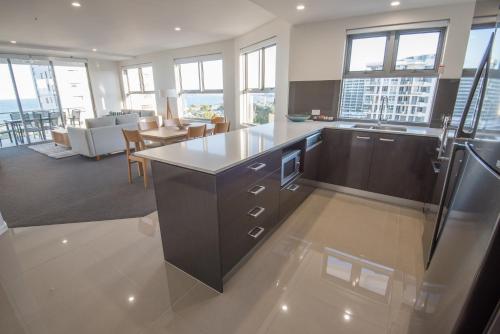 a kitchen with a large island in a room with windows at Verve on Cotton Tree in Maroochydore