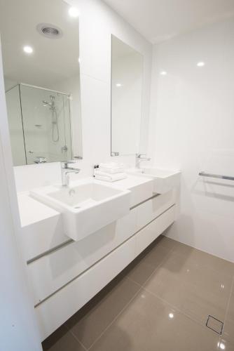a white bathroom with two sinks and a mirror at Verve on Cotton Tree in Maroochydore