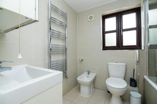 a white bathroom with a toilet and a sink at Comfortable New Refurbished Bedroom in London