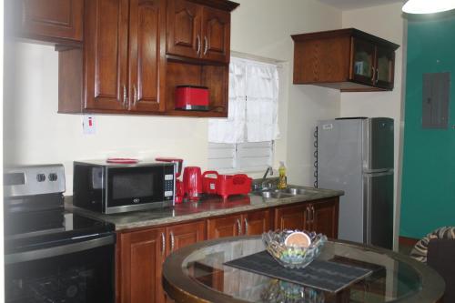 a kitchen with wooden cabinets and a glass table at Serenity at Kensington New Kingston in Kingston