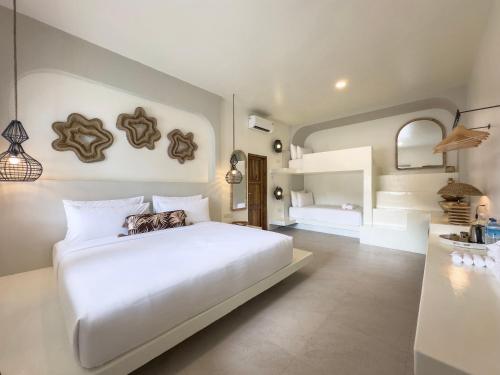 a bedroom with a large white bed and a bathroom at El Tropico Boutique Hotel in Kuta Lombok