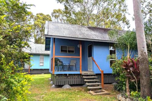 a blue and orange house with a porch at Gumnut Glen Cabins in Yeppoon