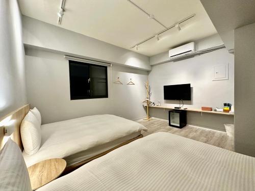 a bedroom with two beds and a flat screen tv at 澄居 live in in Taichung