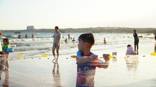 a group of children playing in a net on the beach at Stop And Go Làng Chài Bàu Trắng in Ấp Thiẹn Ái
