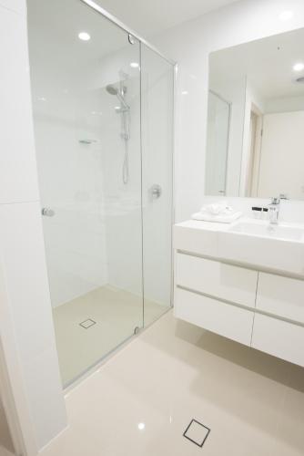 a white bathroom with a shower and a sink at Verve on Cotton Tree in Maroochydore