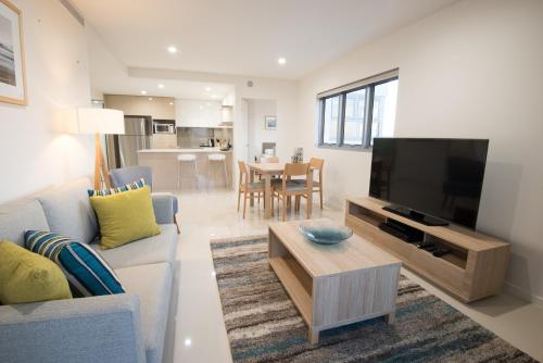 a living room with a couch and a tv at Verve on Cotton Tree in Maroochydore