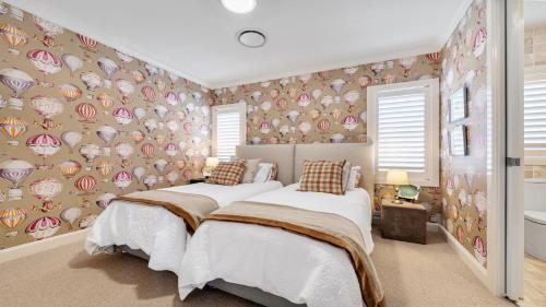 two beds in a bedroom with a wall covered in plates at PIHI Beachfront , Pearl Beach, 5beds, 5 bathrooms in Pearl Beach