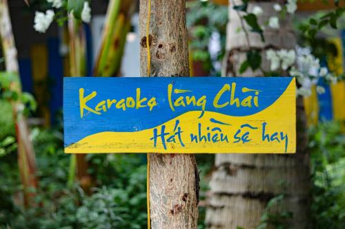 a blue sign on a tree with writing on it at Stop And Go Làng Chài Bàu Trắng in Ấp Thiẹn Ái