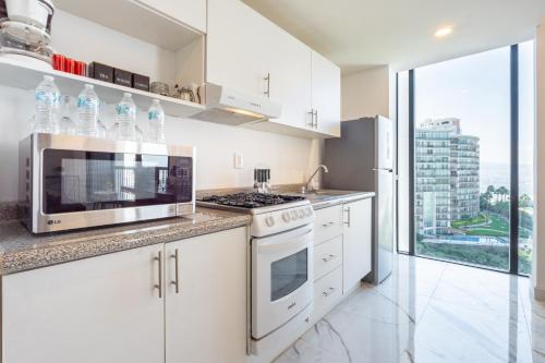 a kitchen with white cabinets and a microwave at Adamant "El10" Depto 2 habitaciones Vista a Qro in Laborcillas