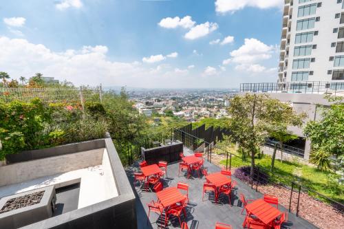 a group of red chairs and tables on a balcony at Adamant "El10" Depto 2 habitaciones Vista a Qro in Laborcillas