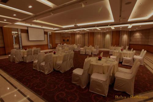 a banquet hall with white tables and chairs and a screen at The Umrao in New Delhi