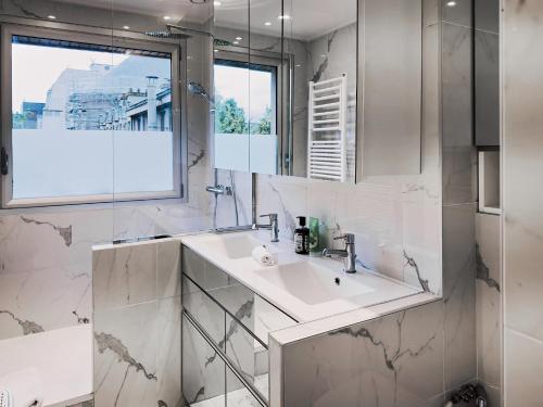 une salle de bain blanche avec un lavabo et un miroir dans l'établissement PenBed -1BR - Proche Champs Elysées, à Paris
