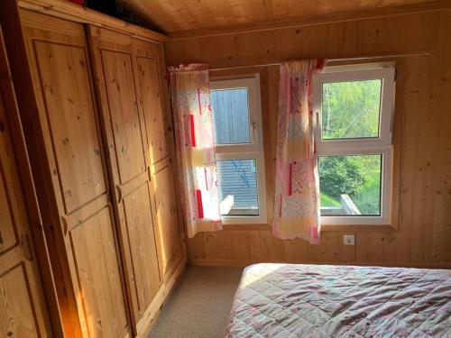 a bedroom with two windows in a wooden cabin at Feriendorf Tauerngast in Hohentauern