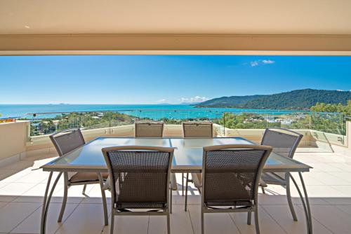 a table and chairs on a balcony with a view of the ocean at Sea Star Apartments in Airlie Beach