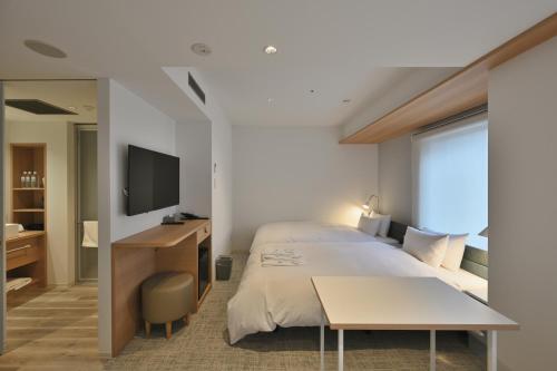 a bedroom with a bed and a desk and a television at Prince Smart Inn Osaka Yodoyabashi in Osaka