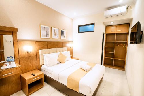 a hotel room with a bed and a television at Selaras Inn Syariah in Yogyakarta