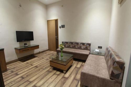 a living room with a couch and a tv at Hotel Ranjeet Akola in Akola