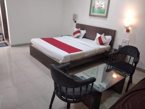 a bedroom with a bed and a table and chairs at Hotel Ranjeet Akola in Akola
