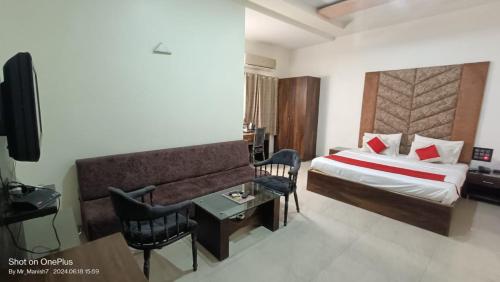 a hotel room with a bed and a couch and a table at Hotel Ranjeet Akola in Akola