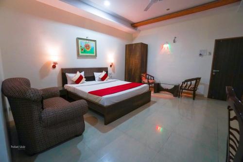 a bedroom with a bed and two chairs at Hotel Ranjeet Akola in Akola