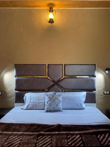 un letto con testiera nera e cuscini bianchi di The Pahadi House a Shimla