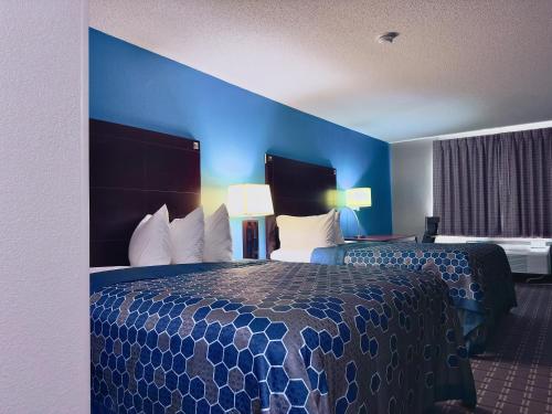 a hotel room with two beds and a blue wall at American Inn Cedar Rapids South in Cedar Rapids
