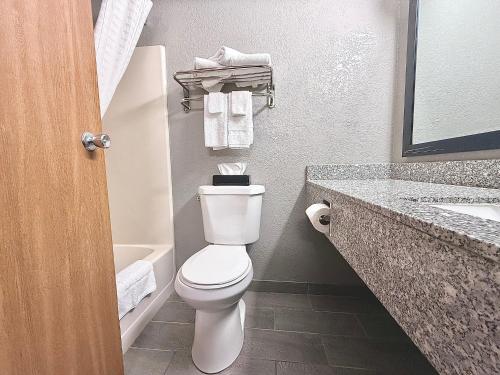 a bathroom with a toilet and a sink with towels at American Inn Cedar Rapids South in Cedar Rapids