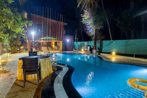 a pool at night with a bar in the middle at Coconut Beach Farm in Alibaug