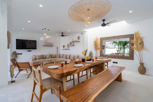 a dining room and living room with a wooden table at Villa Kleoa - Luxury 4 Bedrooms Villa Walking Distance to Seseh Beach in Canggu