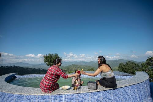 a man and a woman sitting on a table with drinks at Himadvaya- The Himalayan Prism in Almora