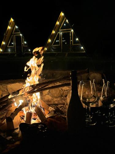 a group of wine glasses and a fireplace at night at Thethi Villas in Theth