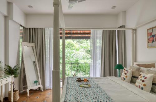 a bedroom with a large bed and a large window at Radiant 1BHK Apartment by tisyastays in Candolim