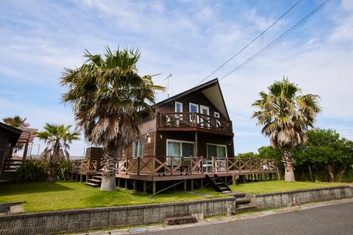 a house with palm trees in front of it at jfハウス - カフェ併設の一棟貸切で楽しむプライベートステイ - サーフポイントまで徒歩5分 in Ichinomiya
