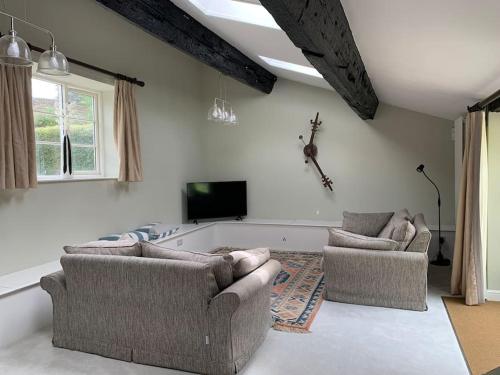 a living room with two couches and a tv at The Cow Shed at Bank Farm in Yeovil