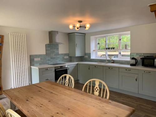 a kitchen with a wooden table and a wooden table and chairs at The Cow Shed at Bank Farm in Yeovil