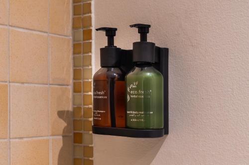 two bottles of soap and shampoo are hanging on a wall at Beautiful 2BR & 4BR Apartments on JBR Beach, Walking Distance to Bluewaters Island - By Sunkissed Holiday Homes in Dubai