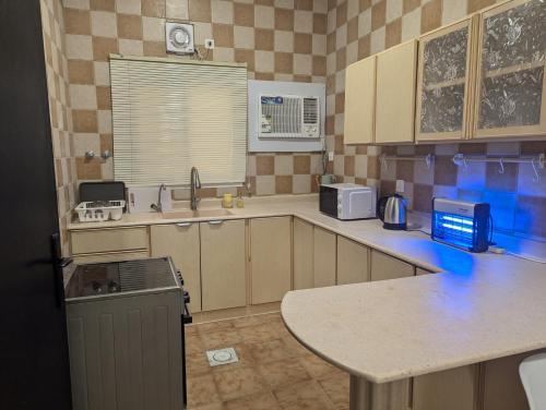 a kitchen with wooden cabinets and a counter top at Ban Luxury Apartments in Al Khobar