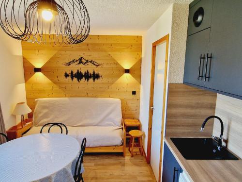 Cette chambre comprend un lit, une table et une cuisine. dans l'établissement Charmant appart 2P cabine, rénové, balcon, parking gratuit, pied des pistes - FR-1-755-22, à Aime La Plagne