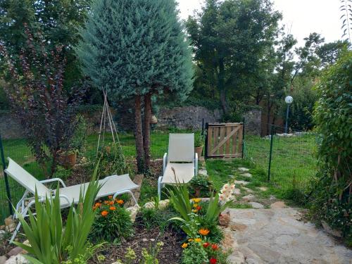 a garden with two white chairs and flowers at Maisonnette au calme in Saint-Vallier-de-Thiey