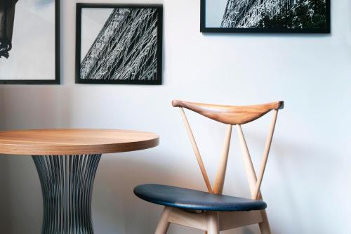 a table and a chair in a room with pictures at Le Méridien Paris Arc De Triomphe in Paris