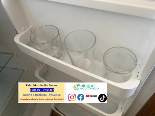 a refrigerator with three empty wine glasses on a shelf at Cabo Frio - Jardim Caiçara - Aluguel Econômico in Cabo Frio