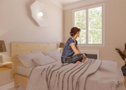 a woman sitting on top of a bed at Appartement Unique! Au centre historique with 2 bedrooms and terrace in Collioure