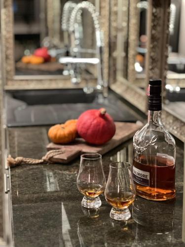 a bottle of alcohol and two glasses on a counter at Vintage Cozy Suite in Vodno