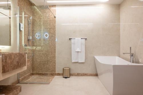 a bathroom with a tub and a shower and a sink at Vender Hotel in Taif