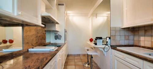 une cuisine avec des armoires blanches et un comptoir dans l'établissement Cannes - Sea View- Swimming Pool - Parking - Beach, à Cannes