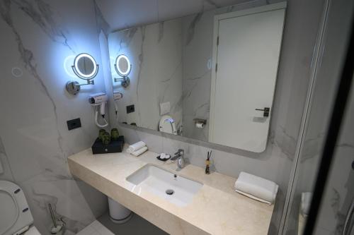 a bathroom with a sink and a large mirror at Holiday Hotel in Tirana